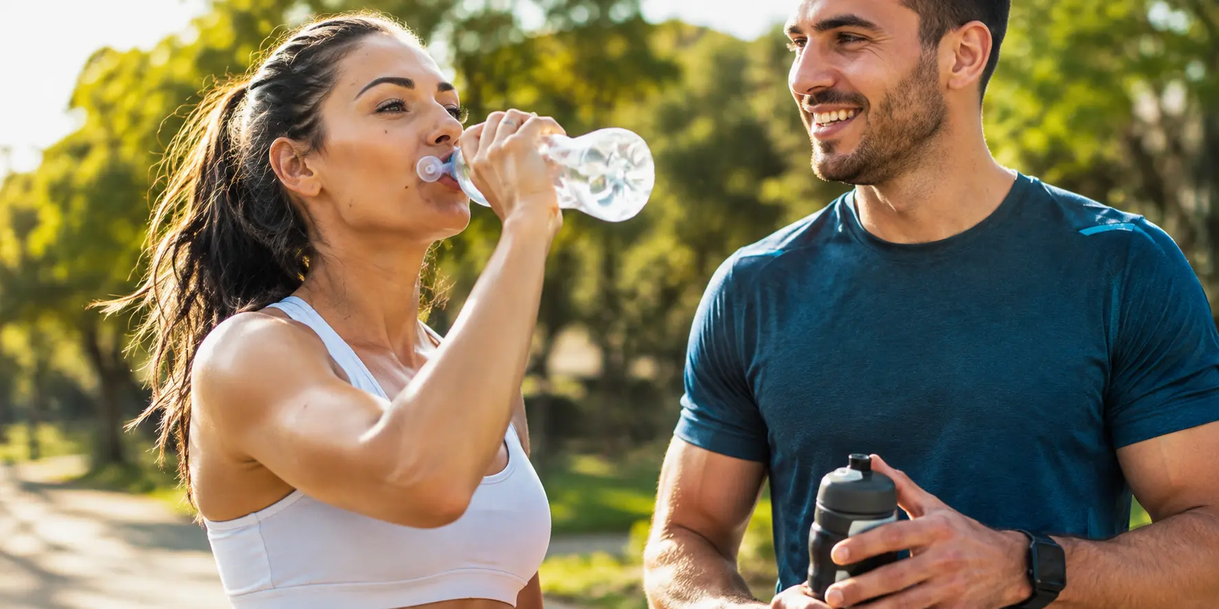 Pareja hidratándose al aire libre después de entrenar